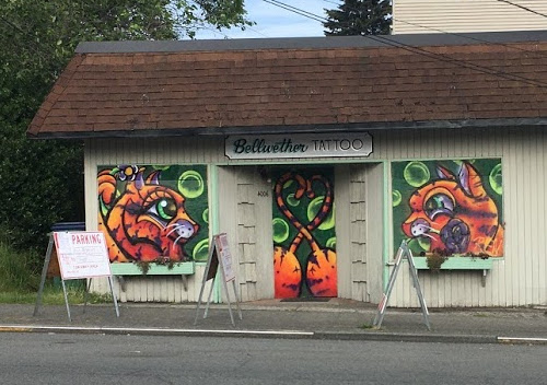 Picture of building with doors and windows covered by plywood and artistic orange cat heads drawn on the window coverings.