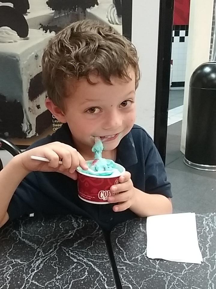 Picture of Calvin grinning while holding up blue ice cream and a gummy worm hangs out of his mouth.