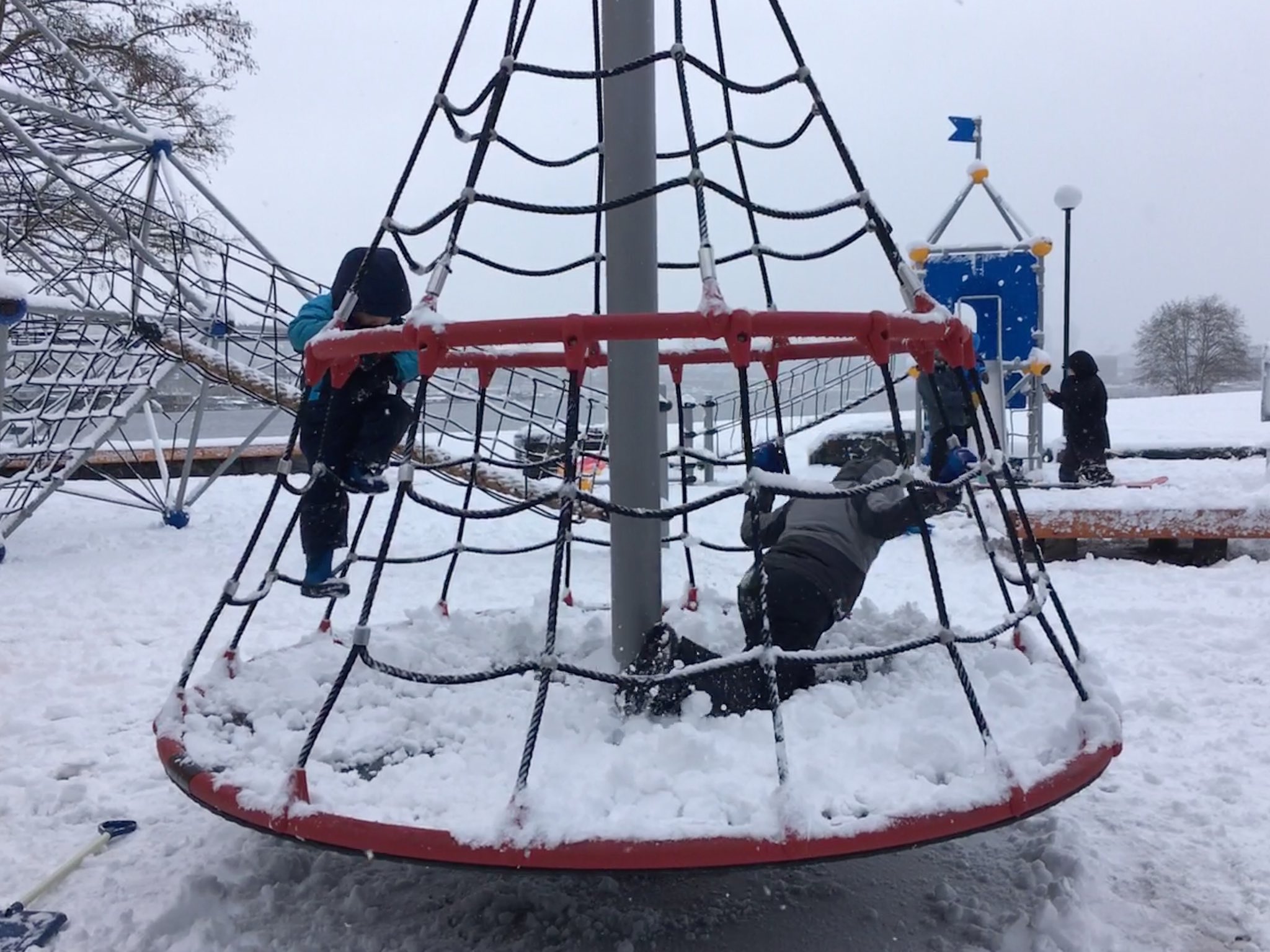 Calvin and Julian, bundled up in snow clothes, are on a pyramid shaped piece of playground equipment.
