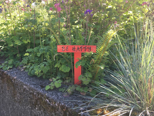 Wood in the shape of a T. Across the top it says "Be Happy".