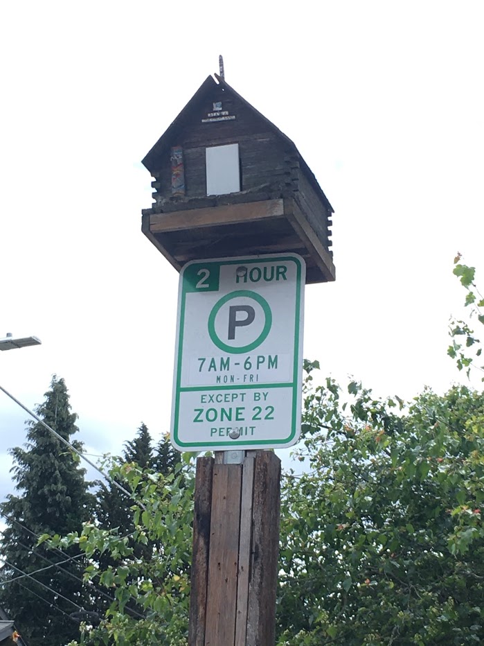 Birdhouse on top of 2 hour parking limit sign.