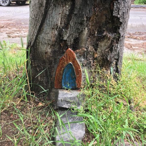 Gothic-style fairy door in tree trunk.