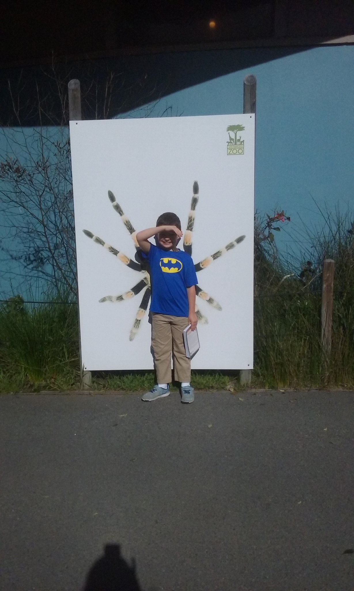 Calvin standing in front of a large spider picture so it looks like he has spider legs coming out of his body.
