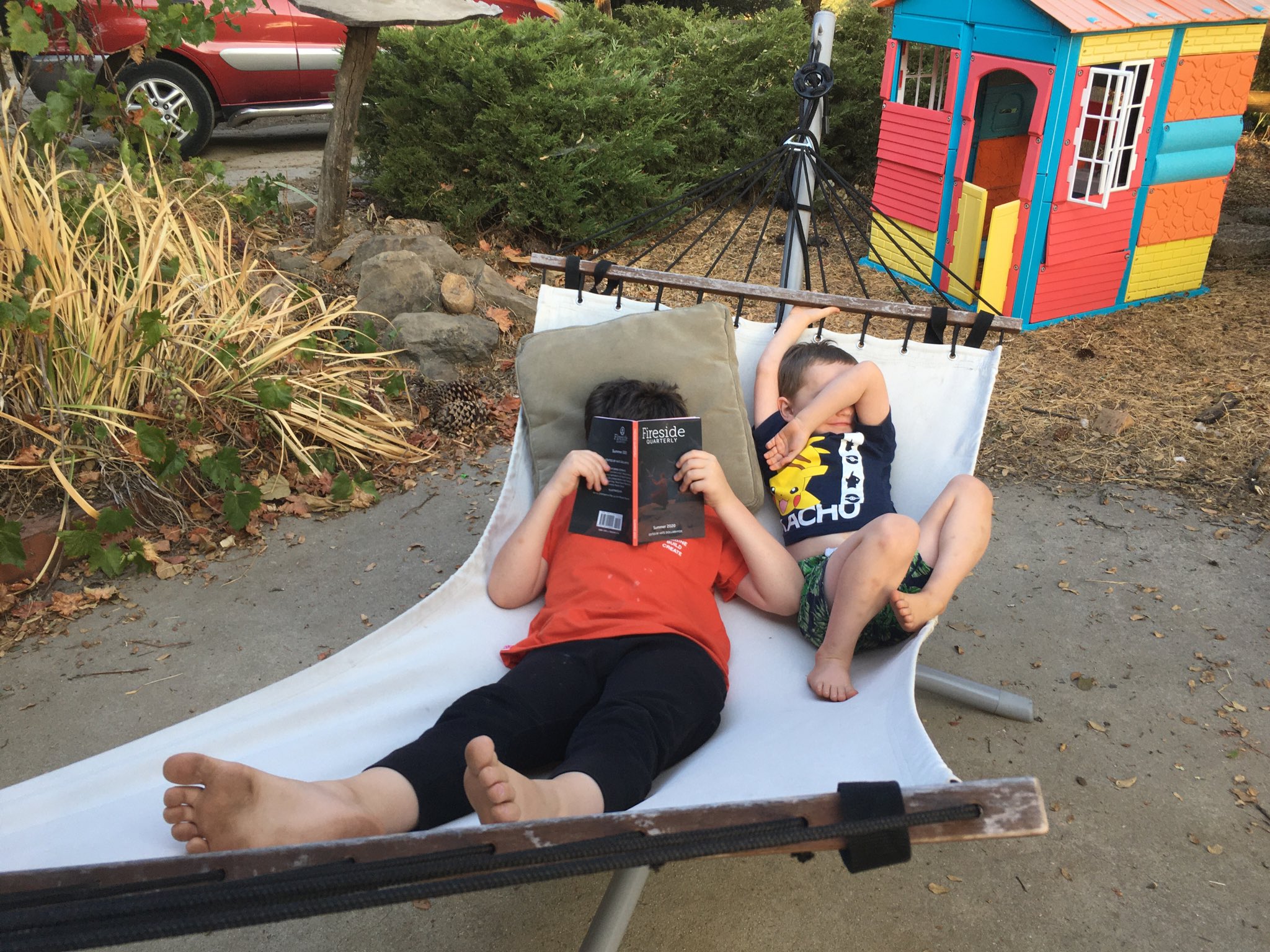 Calvin and Julian laying on a white hammock. Calvin is covering his face with a Fireside Magazine and Julian is covering his face with his arm.