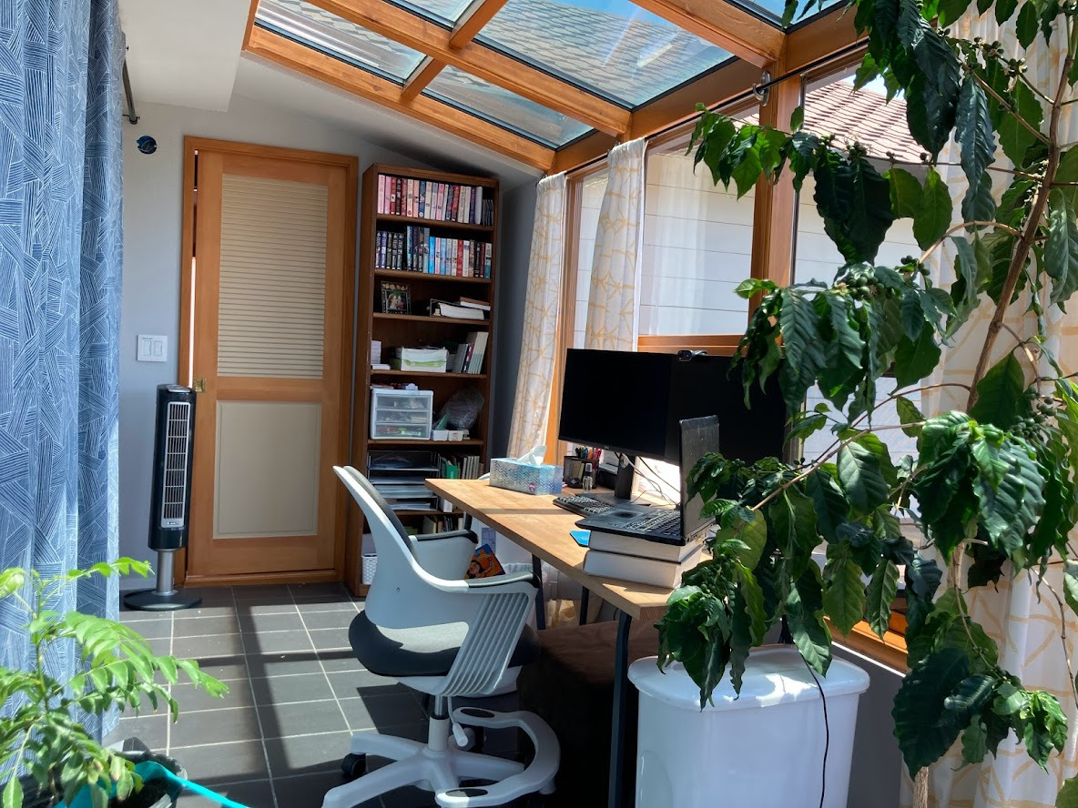 View of the sunroom office from the far corner. Can see old desk and chair as well as bookcase and hall doorway.