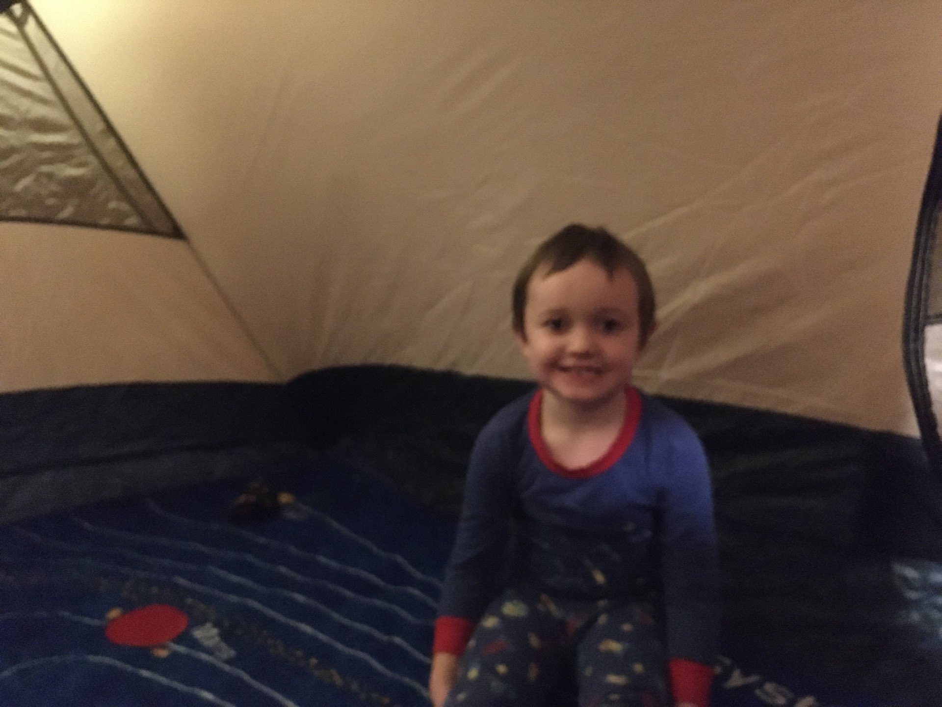 Julian, in a tent, smiling at the camera.